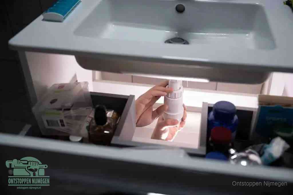 Een pompfles met zeep boven een wastafel, de heet water en afwasmiddel-methode om een vetprop in de afvoer los te maken in Nijmegen