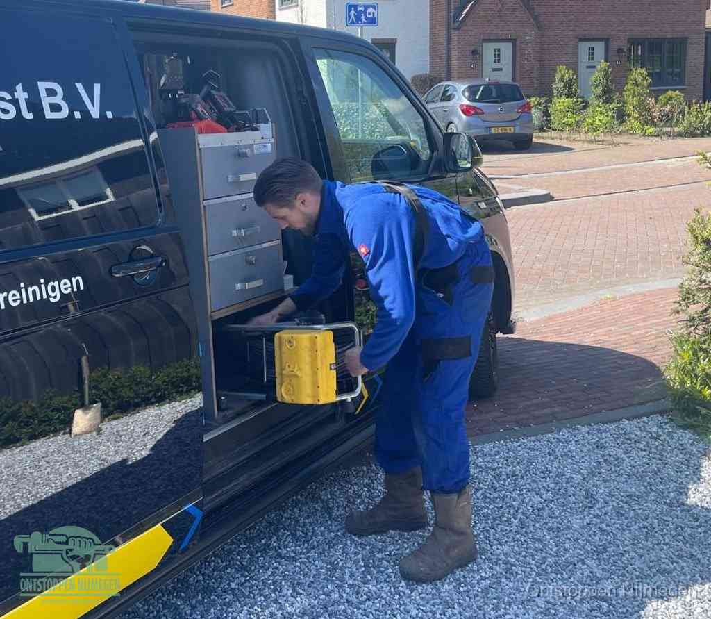 Een monteur pakt buiten op de oprit gereedschap uit de bedrijfsbus, het moment om een professional in te schakelen voor een verstopte afvoer in Nijmegen