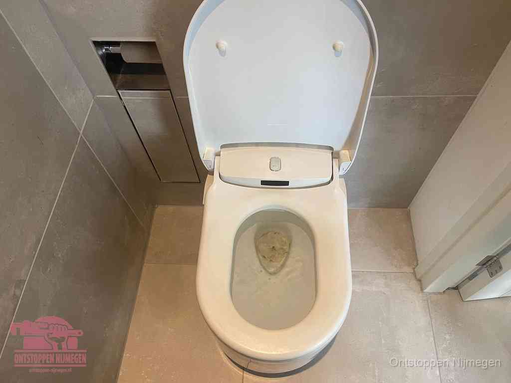 Een wit hangtoilet waarin een prop wc-papier op het water blijft drijven, een duidelijk signaal van een verstopte wc in Nijmegen