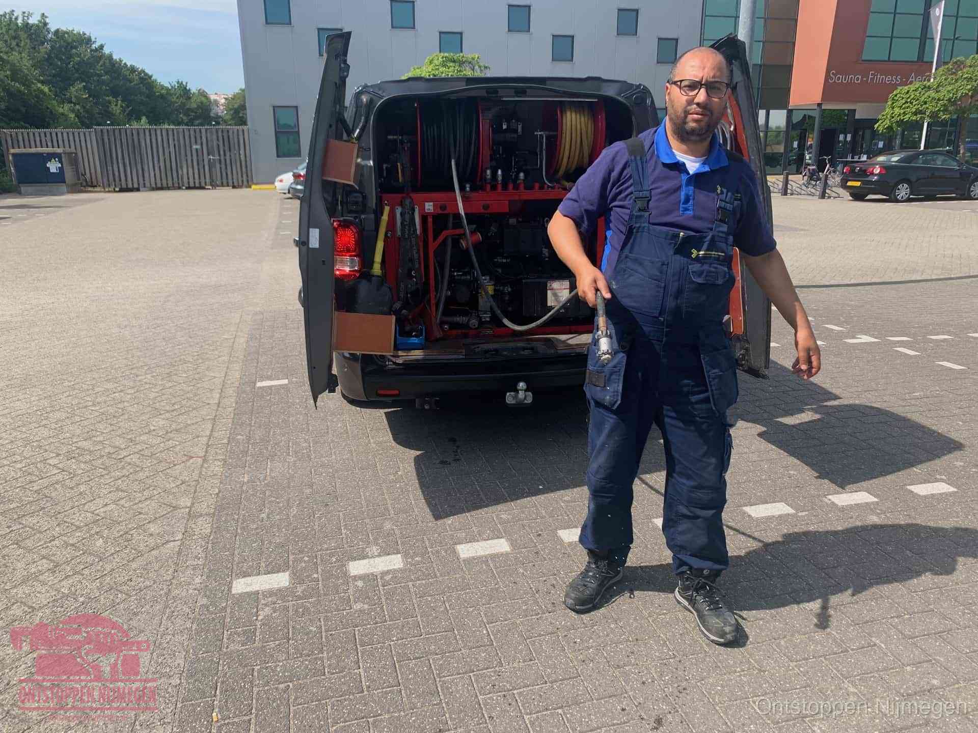 Een monteur bij zijn bestelbus met een hogedruk- en rioolreinigingsunit, klaar om de oorzaak van terugkerende wc-verstoppingen aan te pakken in Nijmegen