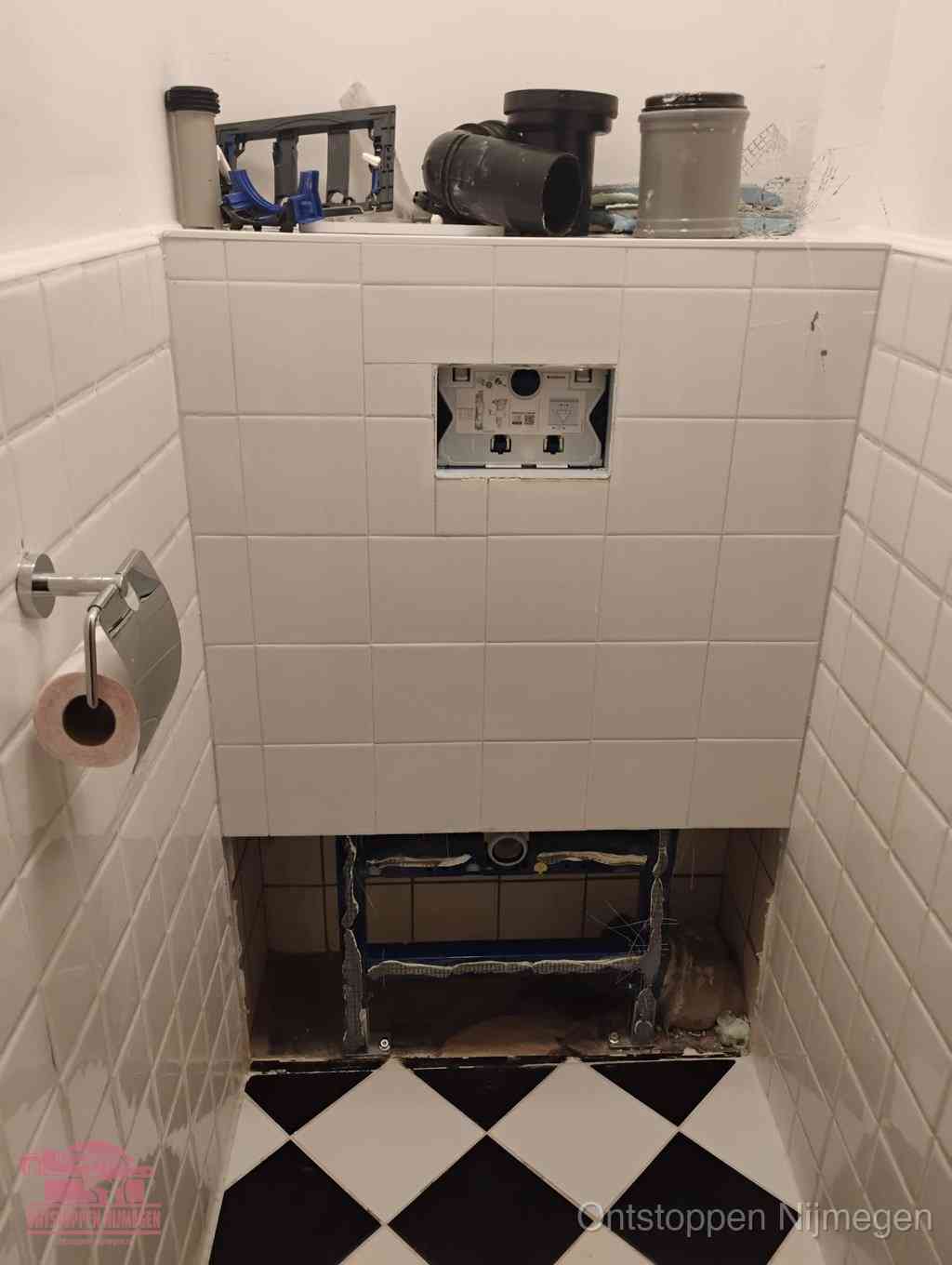 Een toiletruimte waar het hangtoilet en de inbouwreservoir-onderdelen zijn vrijgelegd voor onderhoud, periodiek nazicht voorkomt een wc-verstopping in Nijmegen